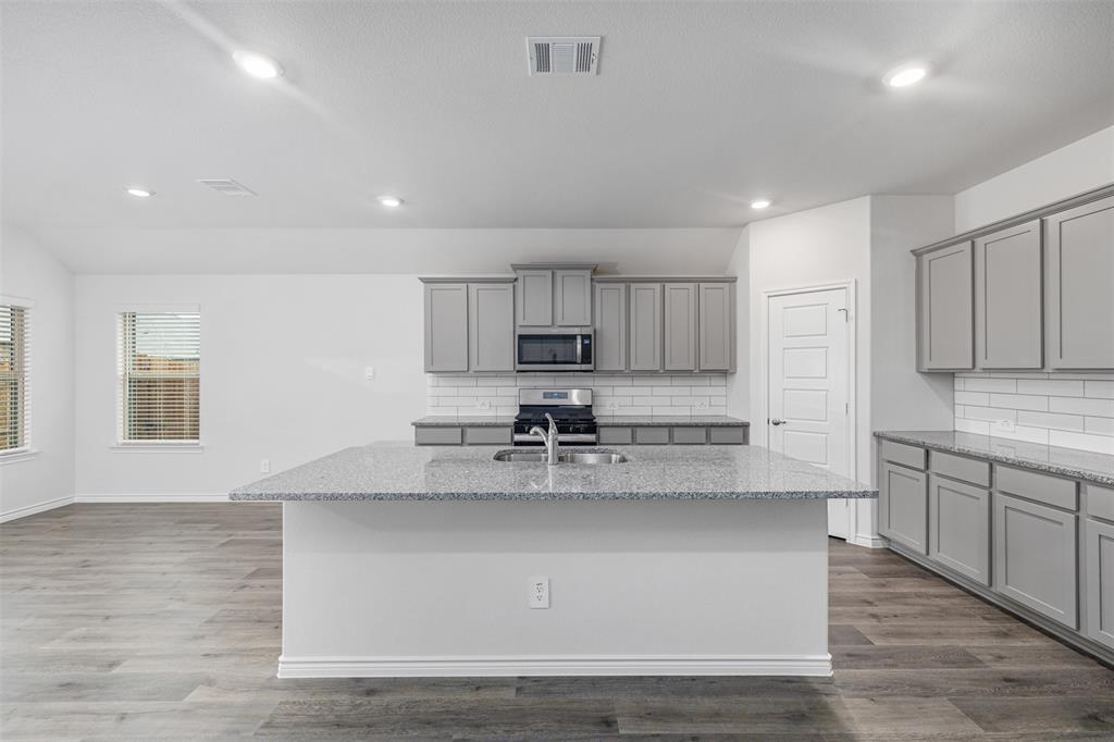 10305 Rambling Brks Lane Aubrey, TX 76227 - Photo 10 of 28 a large kitchen with stainless steel appliances granite countertop a stove a sink and a granite counter tops