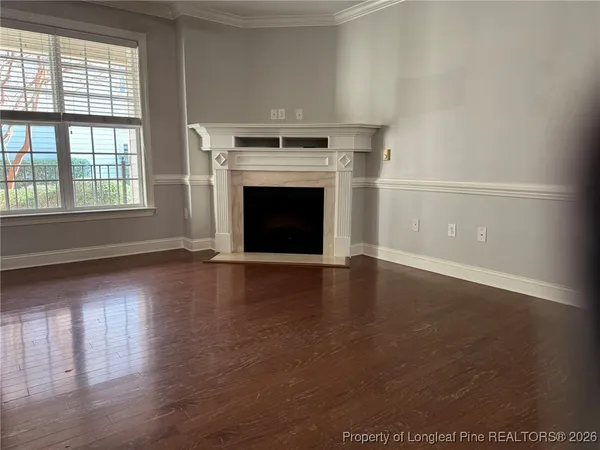an empty room with wooden floor fireplace and windows