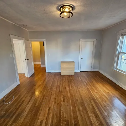 a view of empty room with window and wooden floor