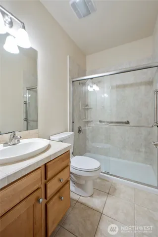 a bathroom with a shower sink vanity mirror and toilet