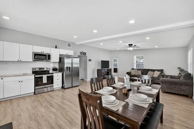 a open kitchen with stainless steel appliances kitchen island granite countertop a stove a sink a refrigerator dining table and chairs