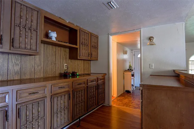 a kitchen with stainless steel appliances granite countertop a refrigerator a sink dishwasher and wooden cabinets with wooden floor