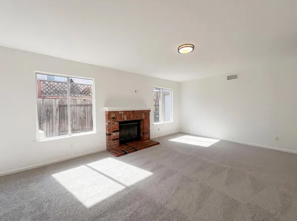 a view of empty room with a fireplace and a window