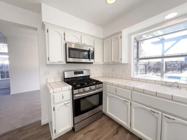 a kitchen with white cabinets appliances and a window