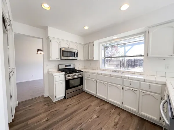 a kitchen with granite countertop white cabinets and stainless steel appliances