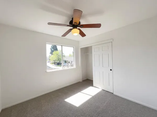a view of an empty room and window and a ceiling fan