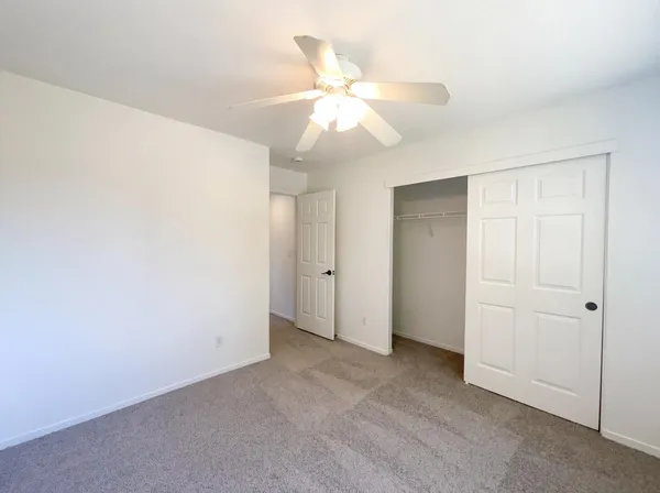 an empty room with a ceiling fan and a window