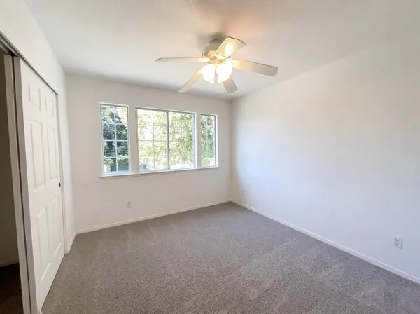 an empty room with windows and chandelier fan
