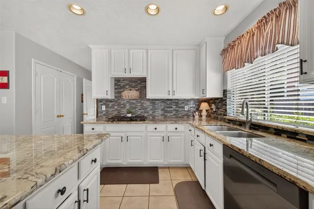 a kitchen with granite countertop a sink stainless steel appliances and white cabinets