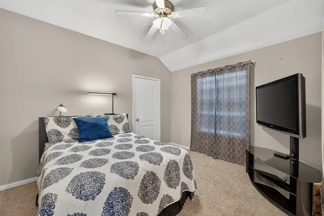 a bedroom with a large bed and a flat tv screen on dresser