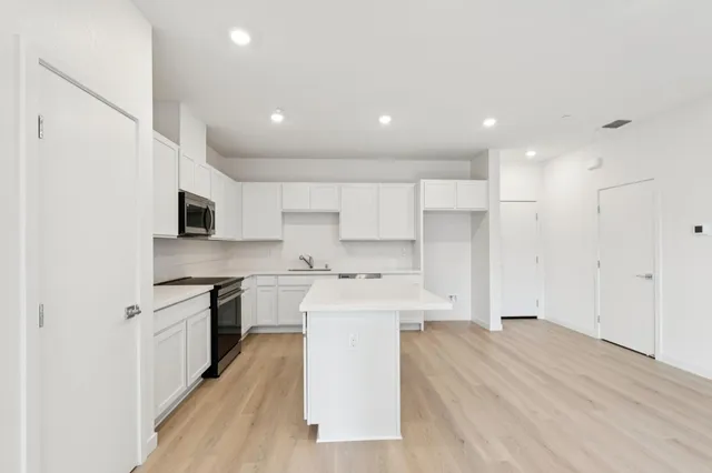 a large kitchen with stainless steel appliances lots of counter space and a sink