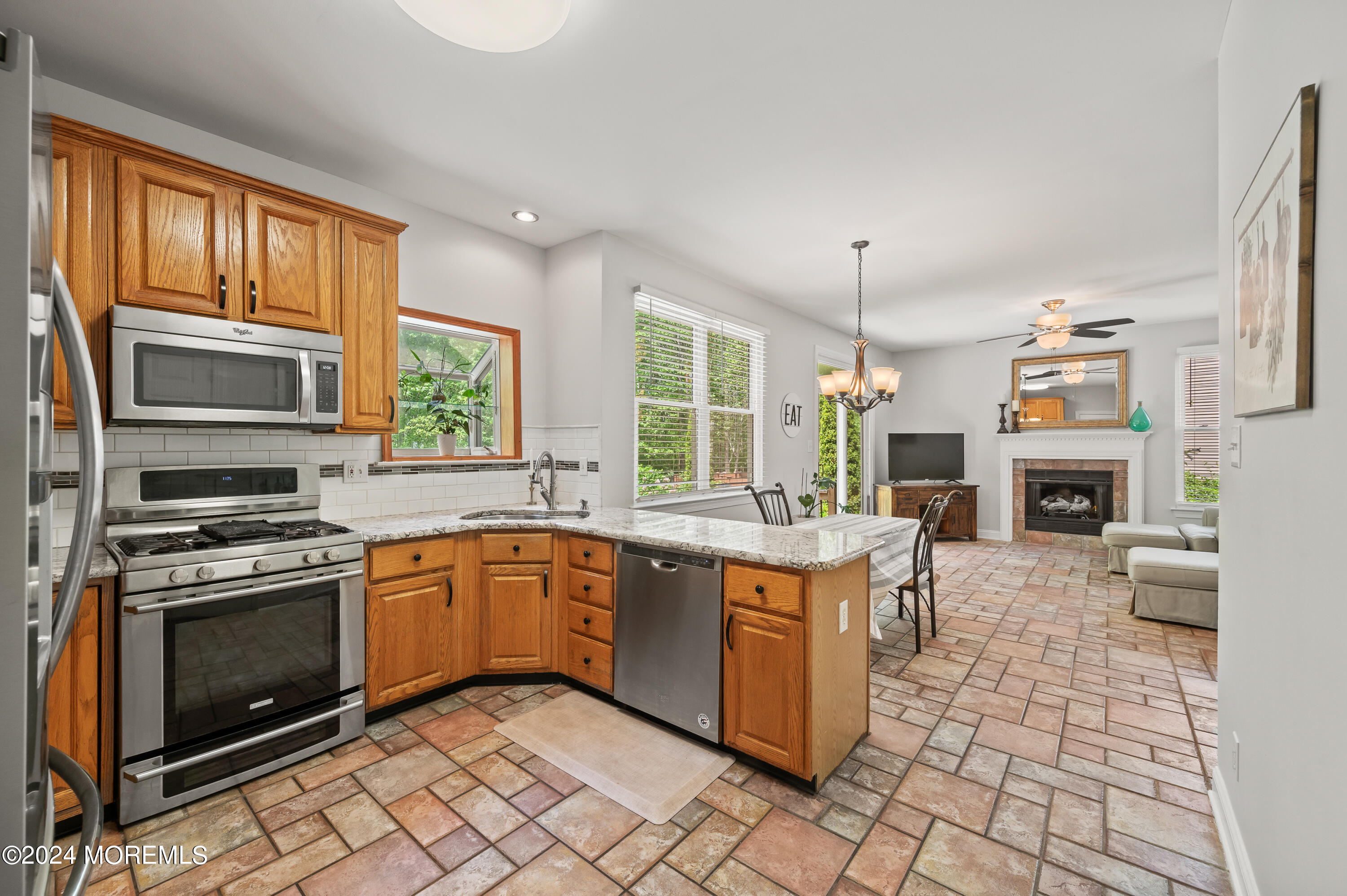 52 Danella Way Howell, NJ 07731 - Photo 19 of 42 a kitchen with stainless steel appliances granite countertop a stove top oven a sink dishwasher a dining table and chairs with wooden floor