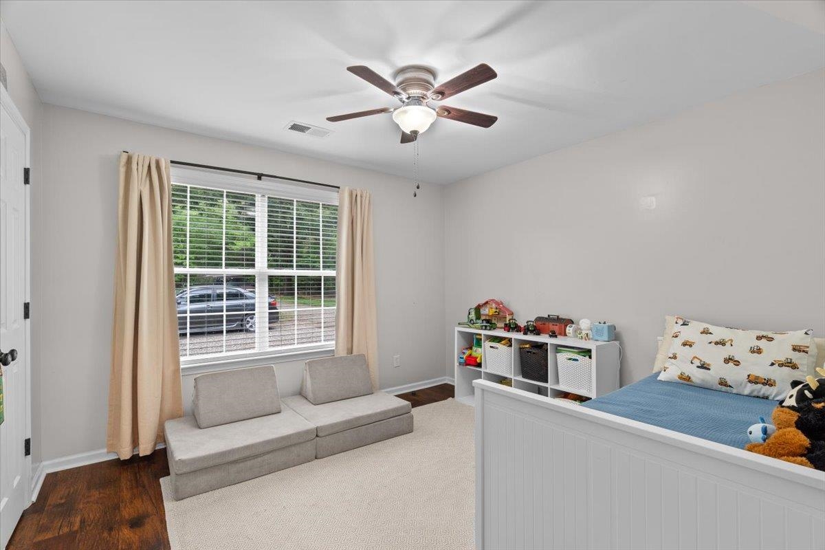 150 Liberty Road Moscow, TN 38057 - Photo 17 of 36 Spacious room featuring rich wood-finish flooring, a large window with white blinds, and a ceiling fan with integrated lighting