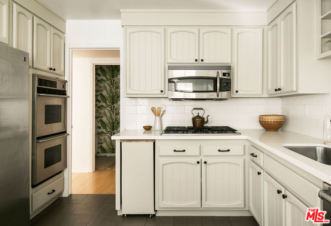 1014 9th Street, Unit 4 Santa Monica, CA 90403 - Photo 7 of 38 a kitchen with white cabinets and stainless steel appliances