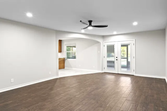 an empty room with wooden floor and a ceiling fan