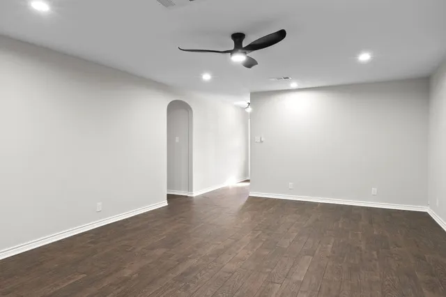 an empty room with wooden floor and a ceiling fan