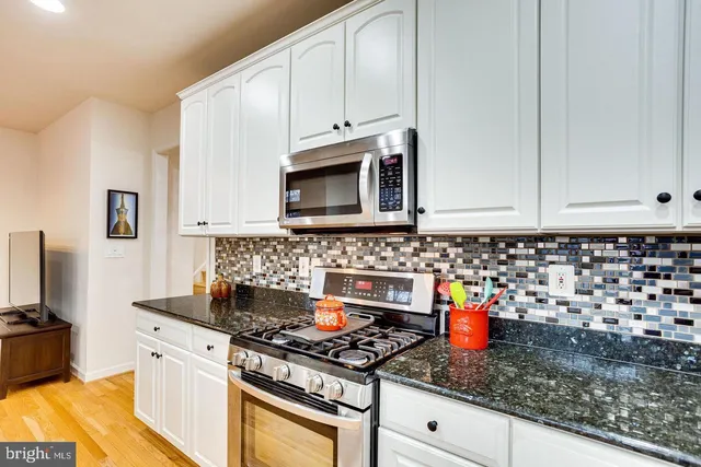a kitchen with granite countertop white cabinets and stainless steel appliances