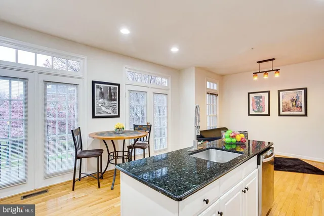 a kitchen island with granite countertop a dining table chairs and wooden floor