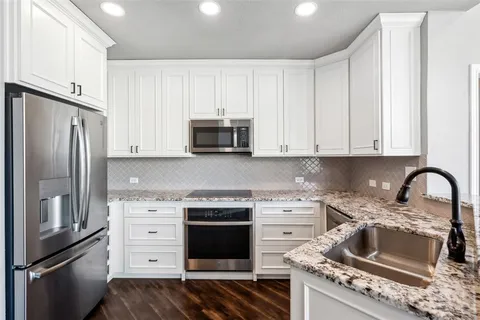 a kitchen with granite countertop a refrigerator stove and sink