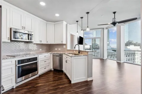 a kitchen with stainless steel appliances kitchen island granite countertop a stove a sink and white cabinets