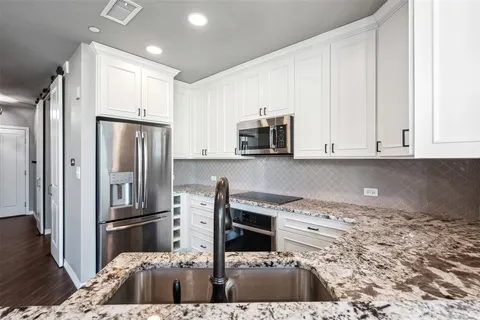 a kitchen with stainless steel appliances granite countertop a refrigerator a stove and white cabinets