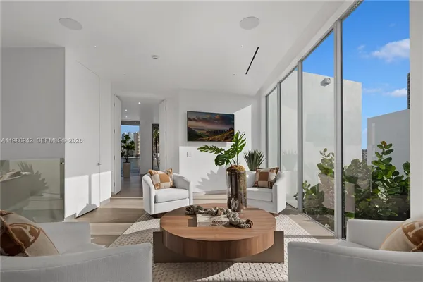 a bedroom with a large bed a flat tv screen and a potted plant