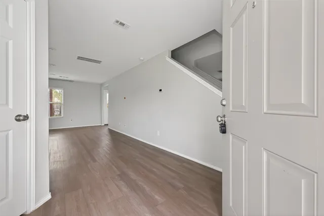 a view of a hallway to an empty room with wooden floor and entryway