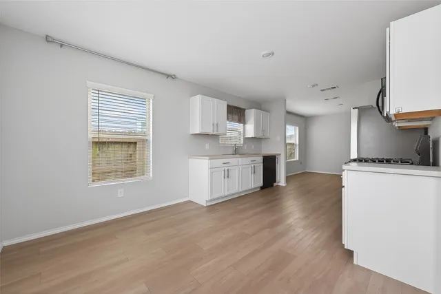 a kitchen with stainless steel appliances granite countertop a stove a sink and white cabinets with wooden floor