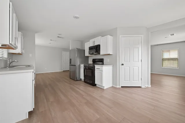 a kitchen with granite countertop a refrigerator and a stove top oven