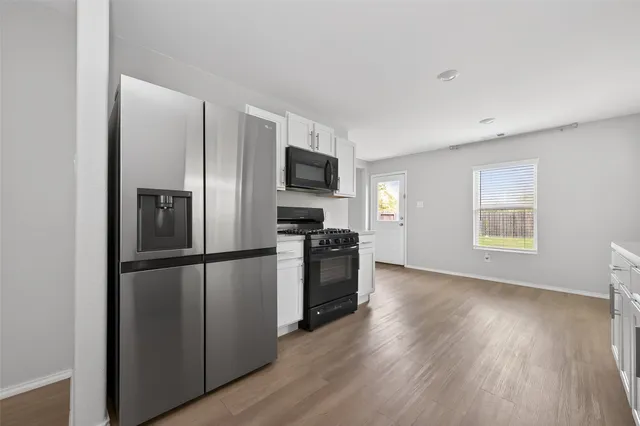 a kitchen with a refrigerator stove and wooden floor