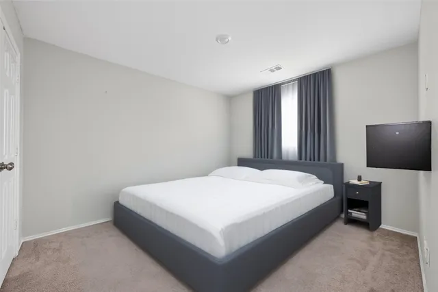 a spacious bedroom with a bed and a flat screen tv