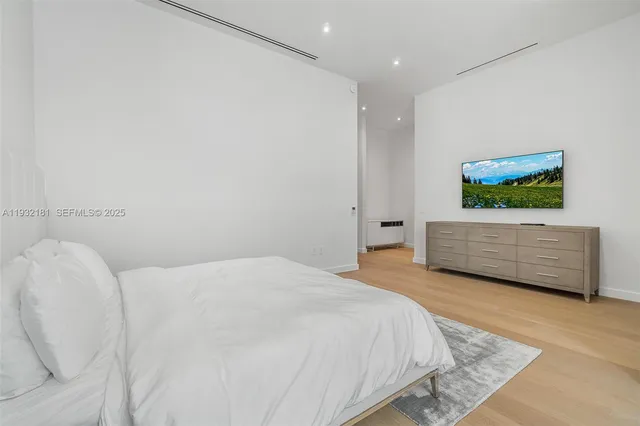 a spacious bedroom with a bed and a flat screen tv