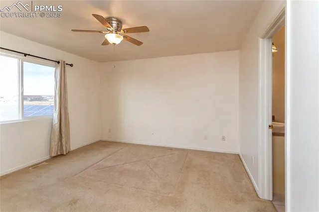 an empty room with a window and a ceiling fan
