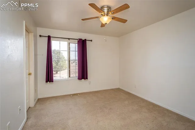an empty room with a window and a fan
