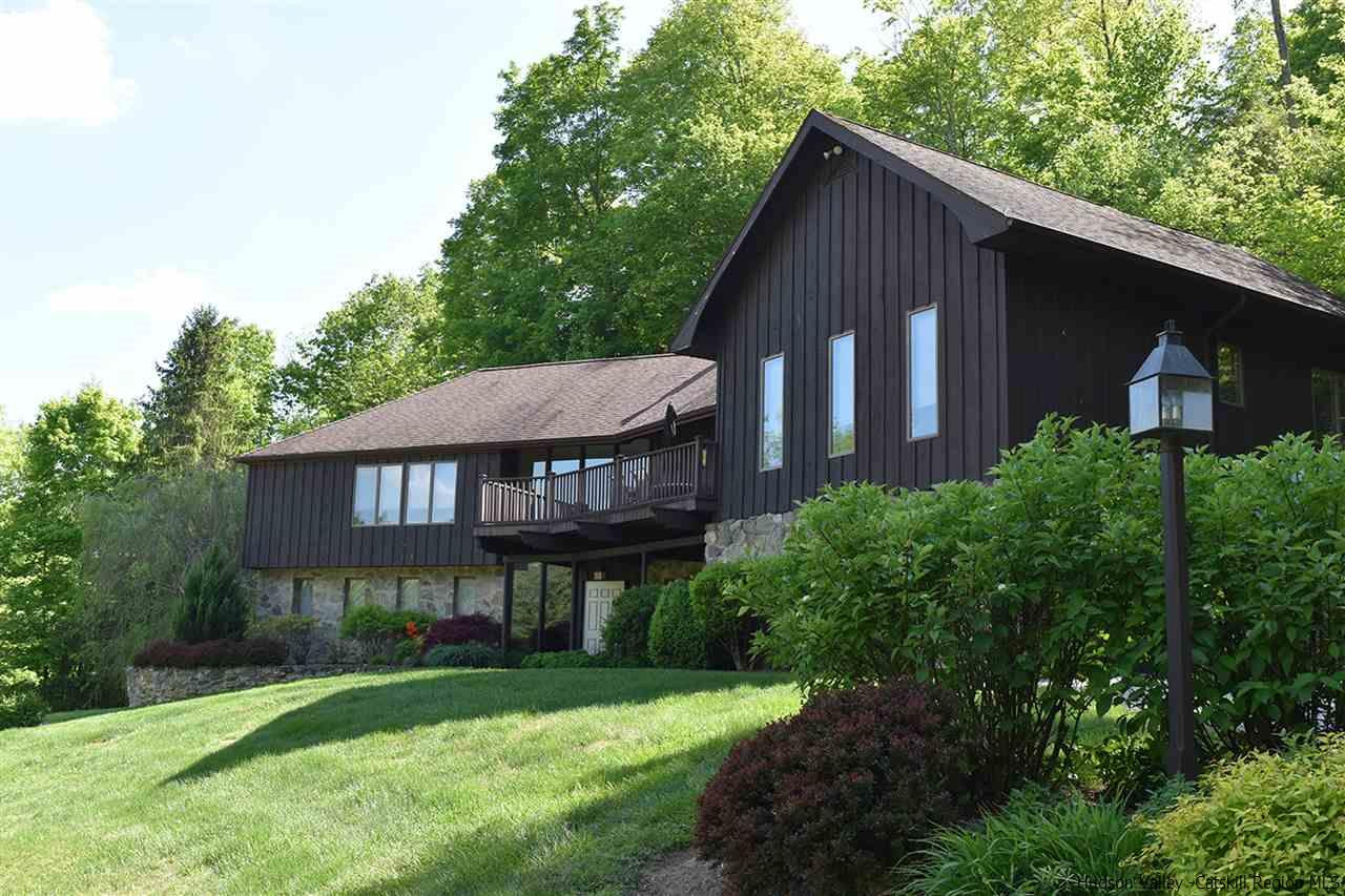 a view of a house with a yard plants and large tree