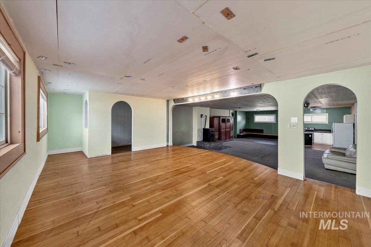 2160 South Five Mile Road Boise, ID 83709 - Photo 33 of 41 Expansive interior featuring wood-finish flooring, arched doorways, multiple windows with wood trim, and a built-in kitchen area with white cabinetry and black countertops