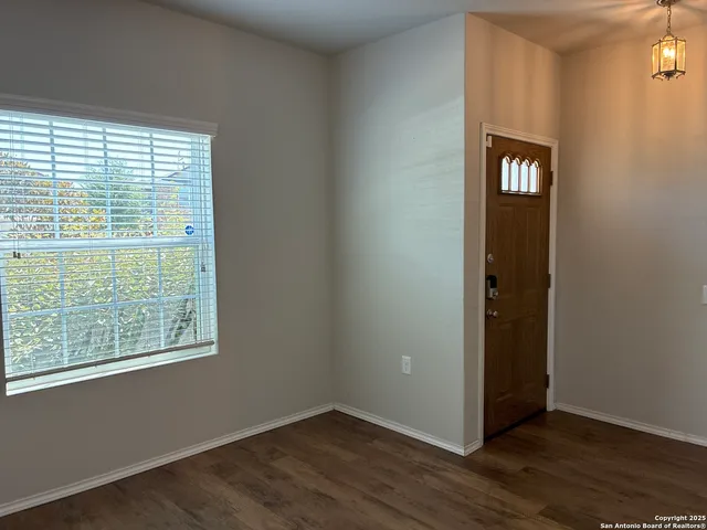a view of an empty room with window and wooden floor