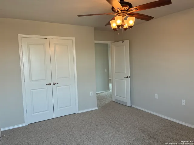 a view of an empty room and a chandelier fan