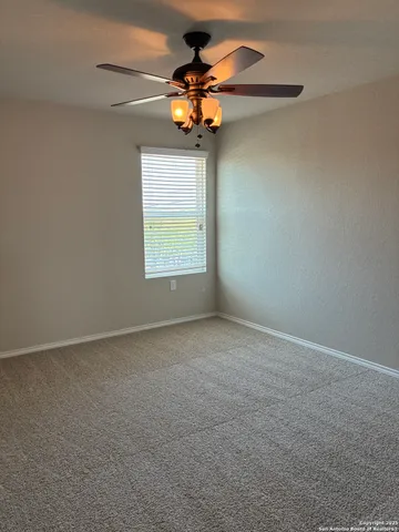a view of an empty room with a chandelier fan