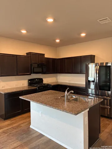 a kitchen with stainless steel appliances granite countertop a sink a stove and a refrigerator