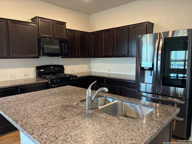 a kitchen with stainless steel appliances granite countertop a sink refrigerator and microwave