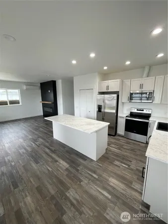 a large white kitchen with wooden floor and a large window