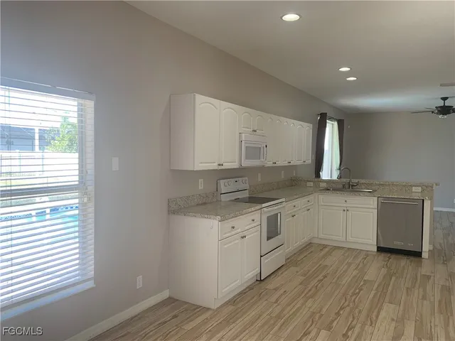 a kitchen with granite countertop white cabinets and white appliances