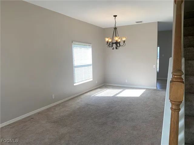 en empty room with windows and chandelier