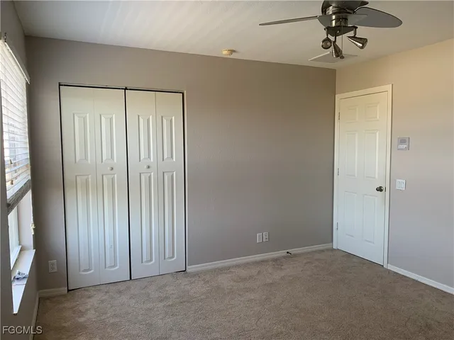 an empty room with a ceiling fan and carpet