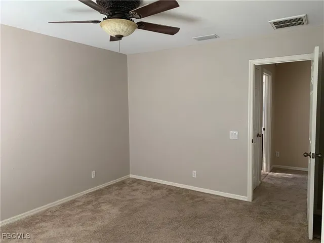 an empty room with a ceiling fan and carpet