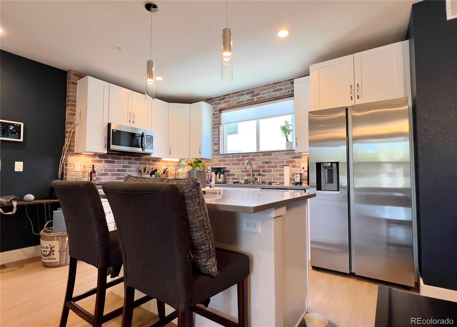 6228 West 38th Avenue Wheat Ridge, CO 80033 - Photo 8 of 38 a kitchen with stainless steel appliances granite countertop a refrigerator a stove a sink a dining table and chairs with wooden floor
