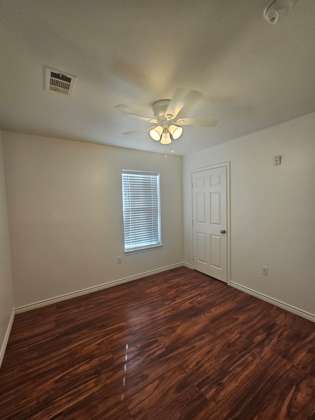 606 Trinity Street Lockhart, TX 78644 - Photo 13 of 23 Rich hardwood floors and a ceiling fan create a comfortable and inviting atmosphere in this flexible space.