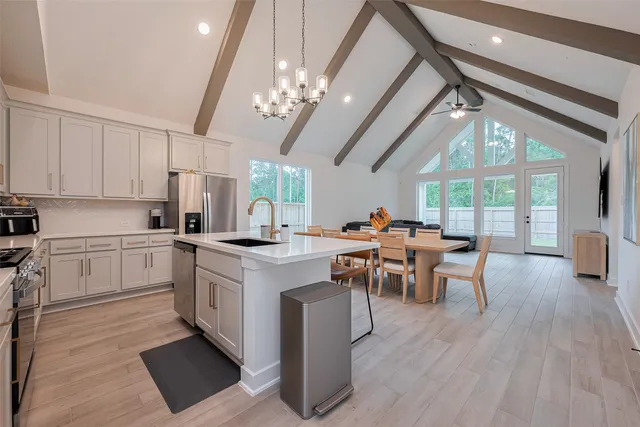 a kitchen with stainless steel appliances a dining table chairs stove refrigerator and microwave