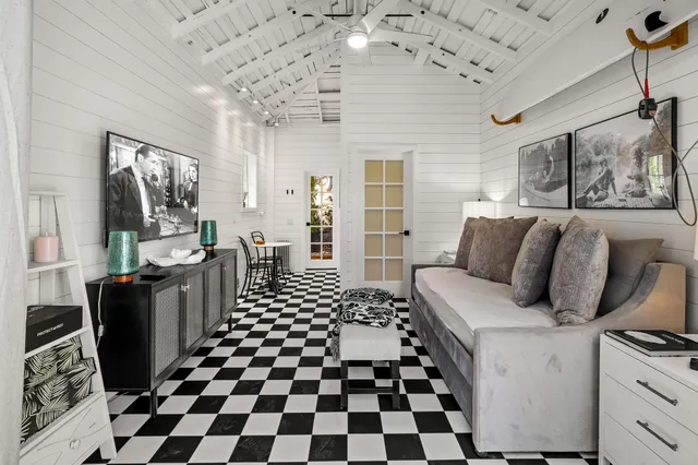 a living room with a black white checkered floor with a gaming machine and wooden floor